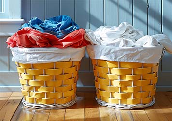 Two laundry baskets with clothing sorted by color. Colored clothing on the left and white clothing on the right.